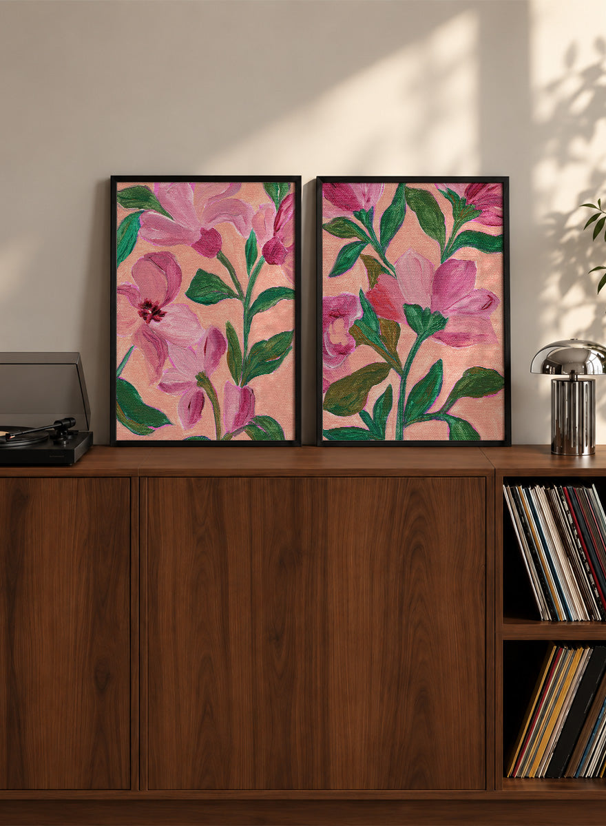 Two framed floral art prints with pink flowers and green leaves on a peach background. Shop Vibrant Pink Botanicals by Nikita Jariwala, a set of 2 floral wall art prints posters featuring oversized pink flowers and lush botanical artwork.