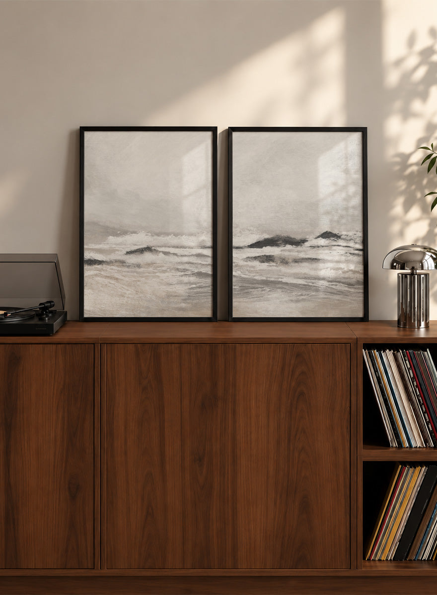 Shop September Coast by Dan Hobday, a set of 2 coastal wall art prints posters featuring rolling waves, dark rocks, misty skies, and soft neutral tones.