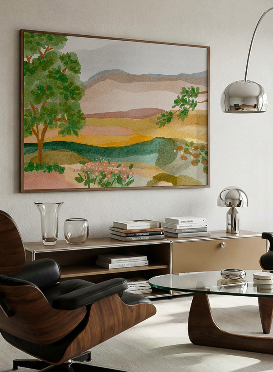 A framed landscape art print featuring a stylized watercolor scene with green trees, layered hills, and a river. Shop Peaceful Valley View by Nikita Jariwala, a serene landscape wall art print poster featuring rolling hills, distant mountains, wildflowers, and soft green tones.