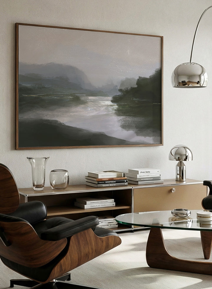 A framed landscape art print depicting a misty river scene with dark green hills, a reflective river, and a pale gray sky. Shop Tranquillitas by Dan Hobday, a contemporary landscape wall art print featuring reflective water, distant hills, dark green trees, and soft gray tones.