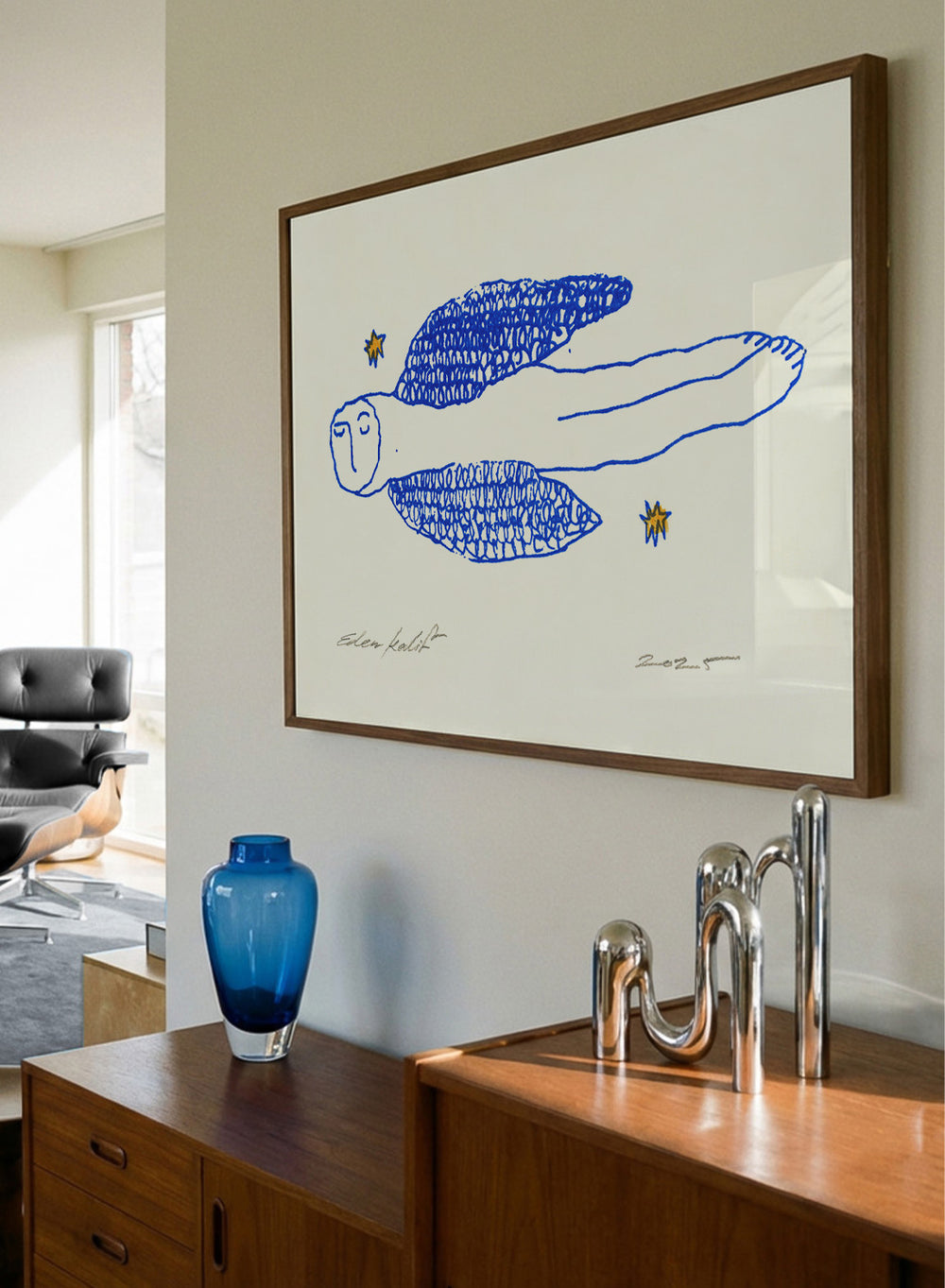Framed artwork of a blue abstract figure with stars on a white background. Angel by Eden Kalif is a modern line art print of a winged figure with blue detail, a contemporary minimalist wall poster with expressive drawing and subtle texture.
