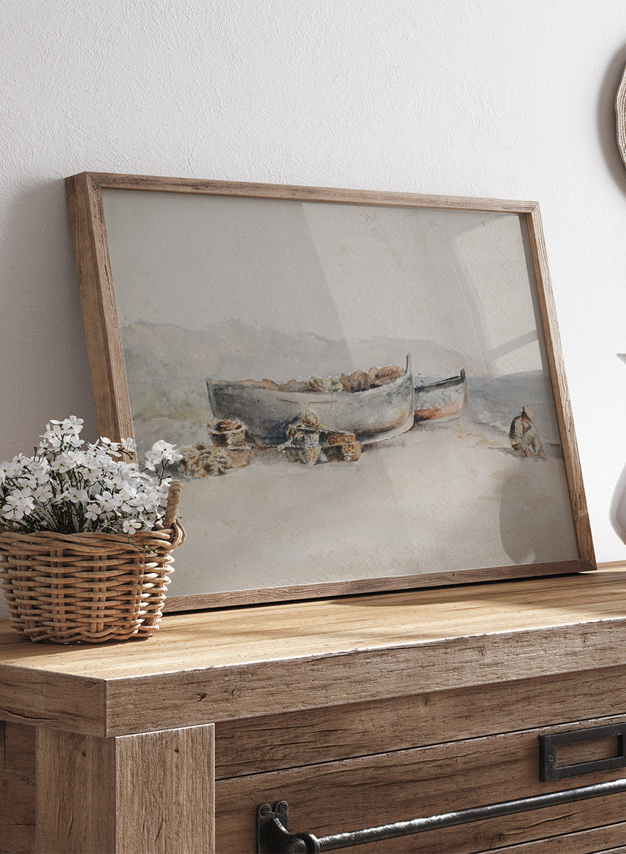 A framed watercolor painting of two small boats on a sandy shore. Fishing Boats on the Shore by Hercules Brabazon Brabazon is a vintage watercolor art print featuring fishing boats, nets, baskets, and a hazy coastal shore.