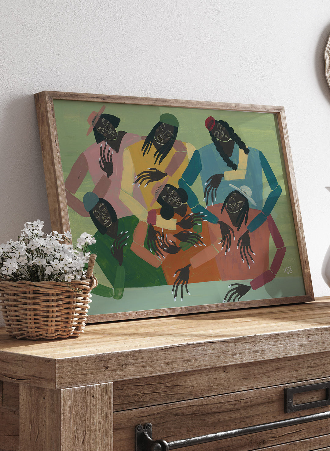 Framed artwork of six people sitting together with colorful clothing on a green background. Gossip by Studio IMO (Ibi Meier-Oruitemeka) is a modern figurative art print with multiple figures, bold color, and contemporary wall poster design.
