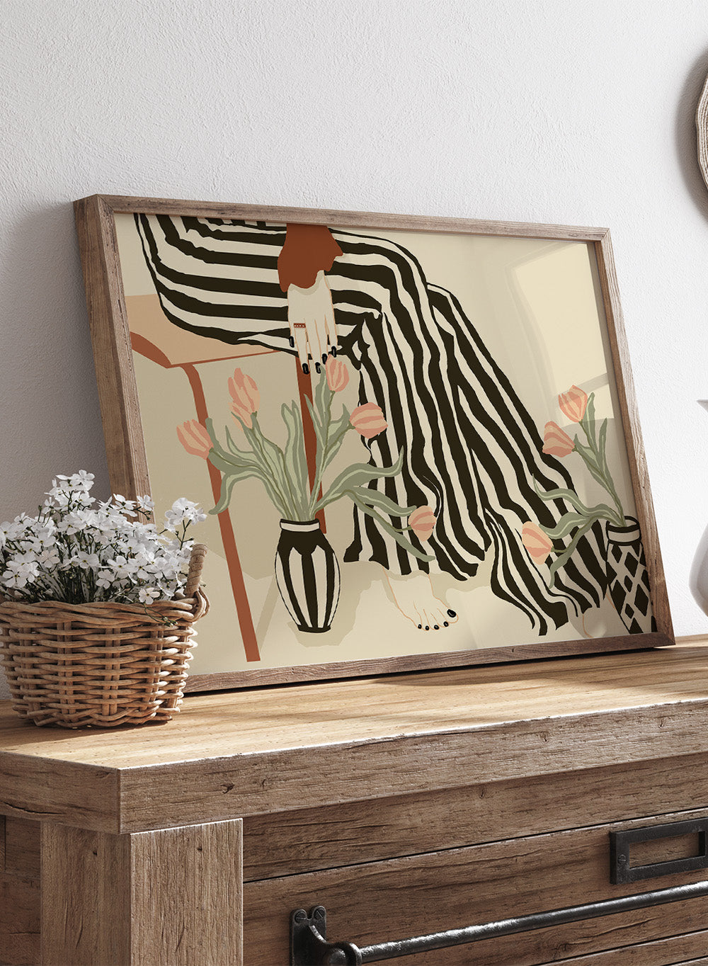 Artistic depiction of a person with striped pants sitting on a chair with floral arrangements. Tulips By My Feet by Sannel Larson is a modern minimalist art print with woman in striped pants and soft tulips. Officially licensed wall poster with framing.