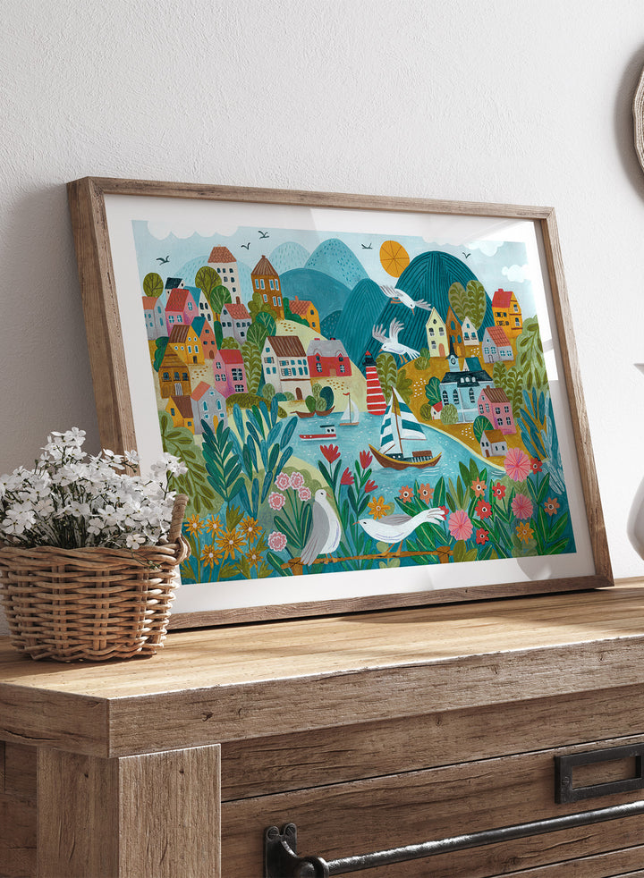 Coastal Village by Caroline Bonne Müller is a colorful coastal town art print with boats, lighthouse, and floral foreground in modern aesthetic illustration style.