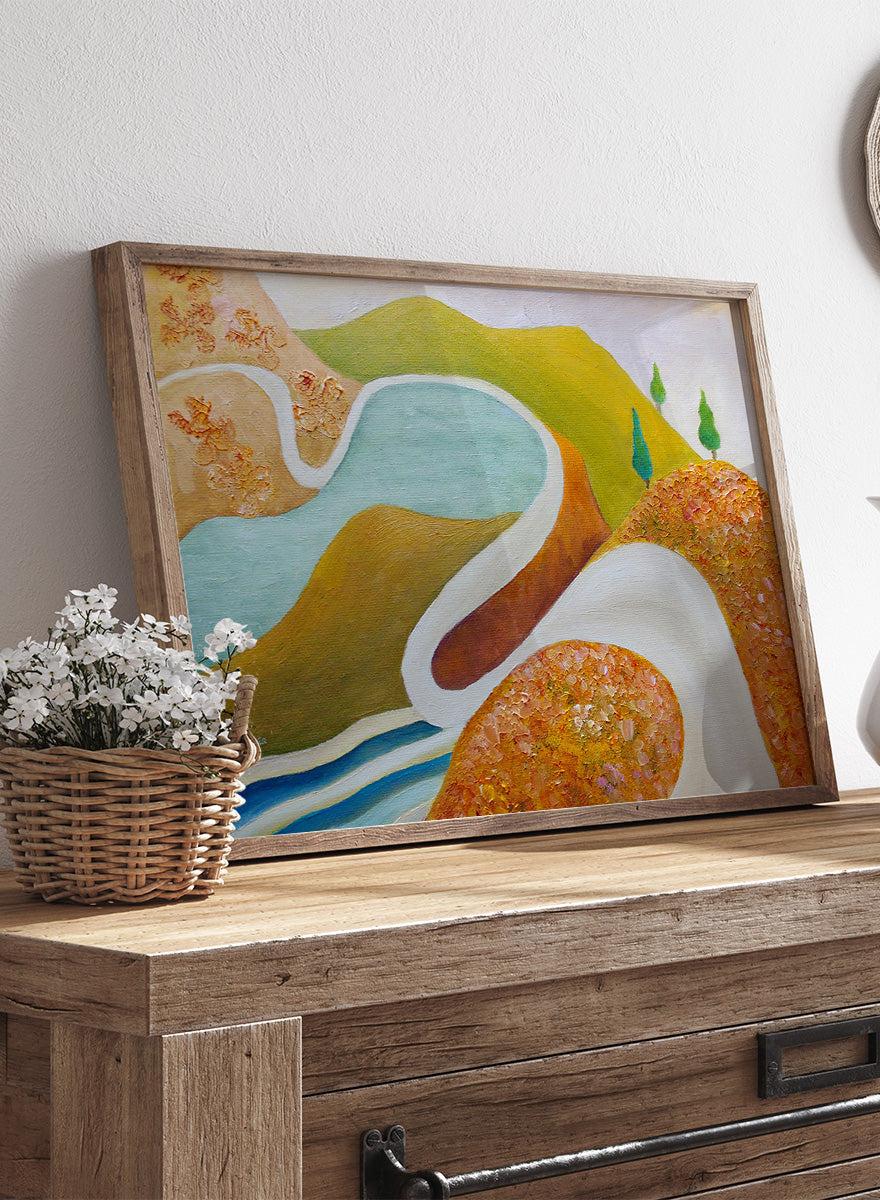 A framed abstract landscape painting featuring winding light blue and white river-like curves, green hills, and textured orange-brown foreground shapes. Shop Serene Valley Path by Angeles M. Pomata, a colorful landscape art print featuring a winding path, river, rolling hills, and warm earthy tones.