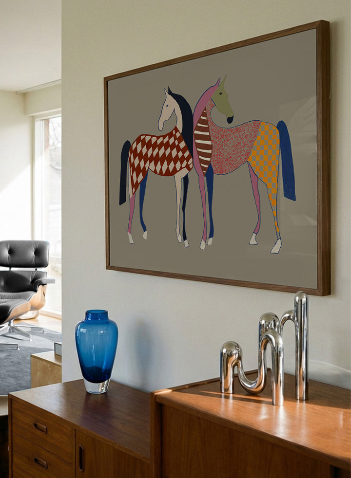 A framed art print featuring two stylized horses with colorful geometric patterns, set against a solid taupe background. Colorful Patterned Horses by The Art Concept animal art print featuring two horses with checks, stripes, florals, and bold playful color.