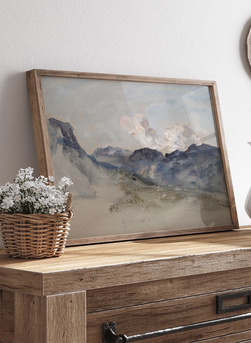 A framed landscape painting featuring blue and gray mountains under a pale sky with soft white clouds. In the Alps by Hercules Brabazon Brabazon is a vintage watercolor art print featuring snowy peaks, blue-grey mountains, soft clouds, and a misty alpine view.