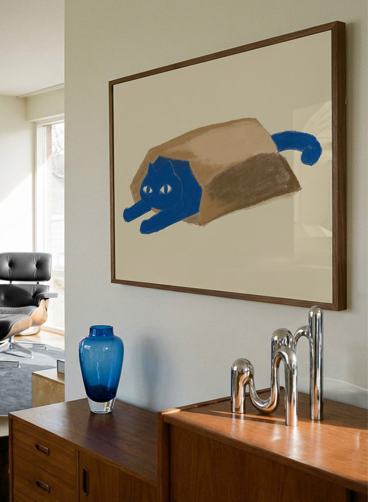 A framed art print featuring a whimsical illustration of a blue cat peeking out from inside a brown paper bag, set against a warm beige background. Blue Cat In A Bag by The Art Concept is a playful minimalist cat art print featuring a blue cat tucked inside a paper bag on a warm cream background.