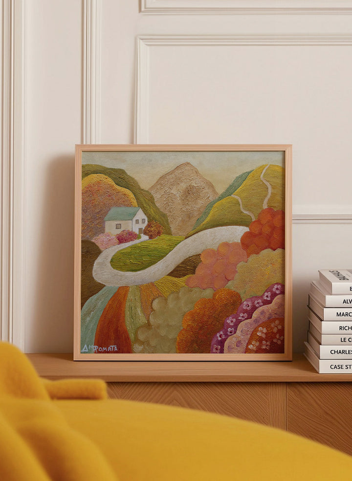 A framed landscape painting featuring a winding white road through colorful hills, a small white house, and a mountain in the background. Shop Colorful Hillside Home by Angeles M. Pomata, an autumn landscape art print featuring a winding road, white country house, rolling hills, and wildflowers.