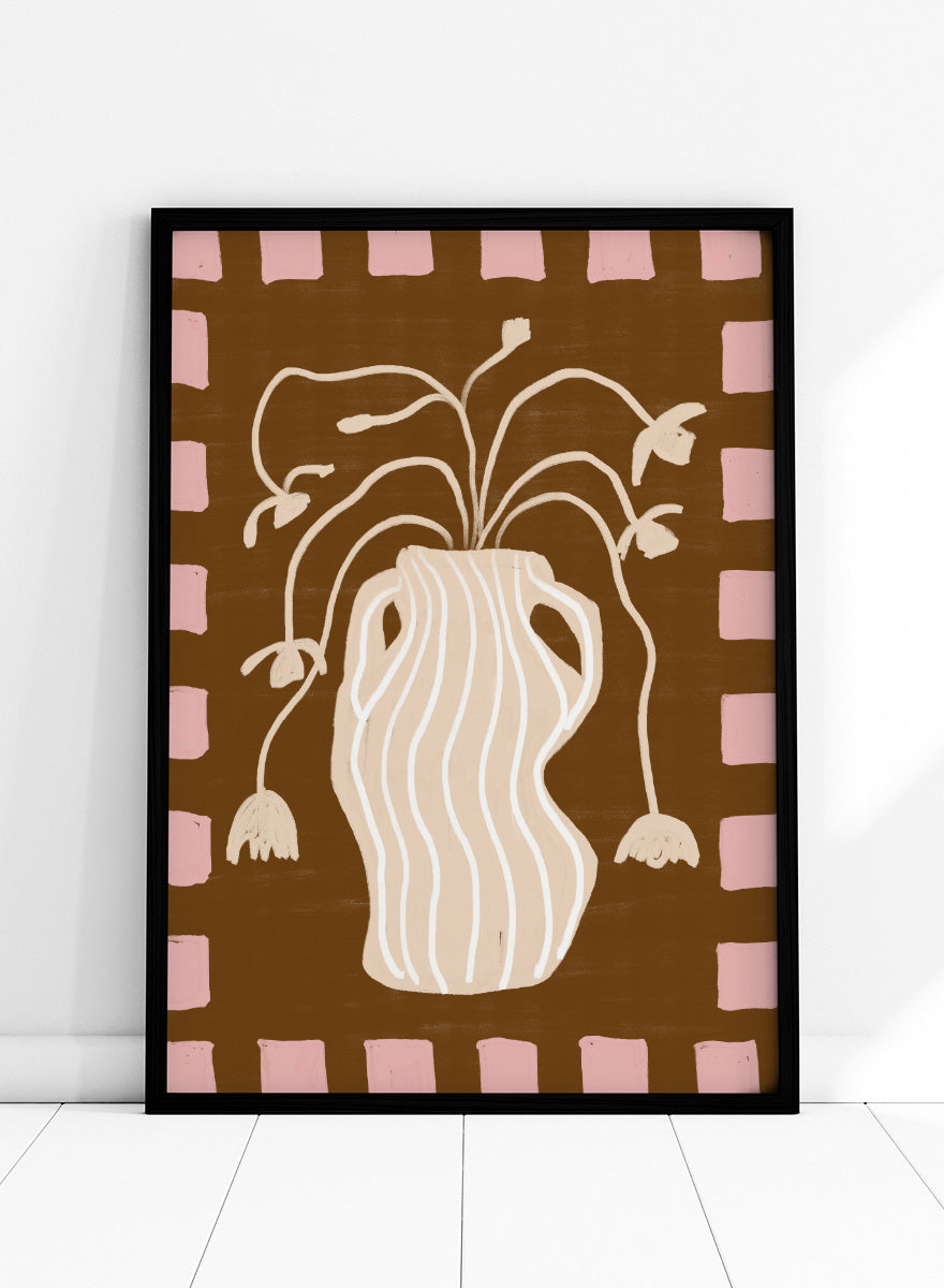 A stylized art print featuring a cream-colored wavy vase with stems and hanging flower buds on a brown background, framed by a pink and brown checkered border. Soft Floral Arrangement by The Art Concept still life art print featuring a striped vase, drooping flowers, warm brown tones, and a soft pink border.
