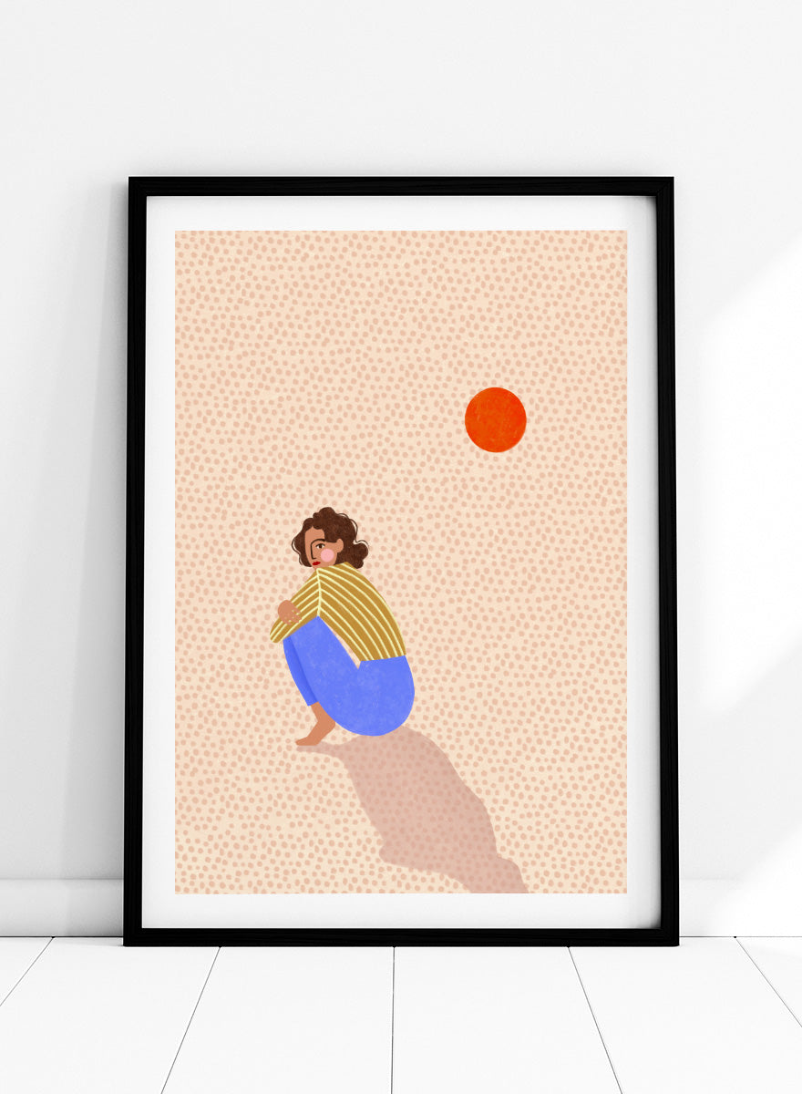 A minimalist art print featuring a stylized illustration of a person crouching in blue pants and a yellow striped top, looking up at a small orange sun against a light beige dotted background, framed with a white mat and black border. Pensive Woman Under Sun by Bea Müller art print featuring a seated woman beneath an orange sun in bold blue, mustard, and soft neutral tones.
