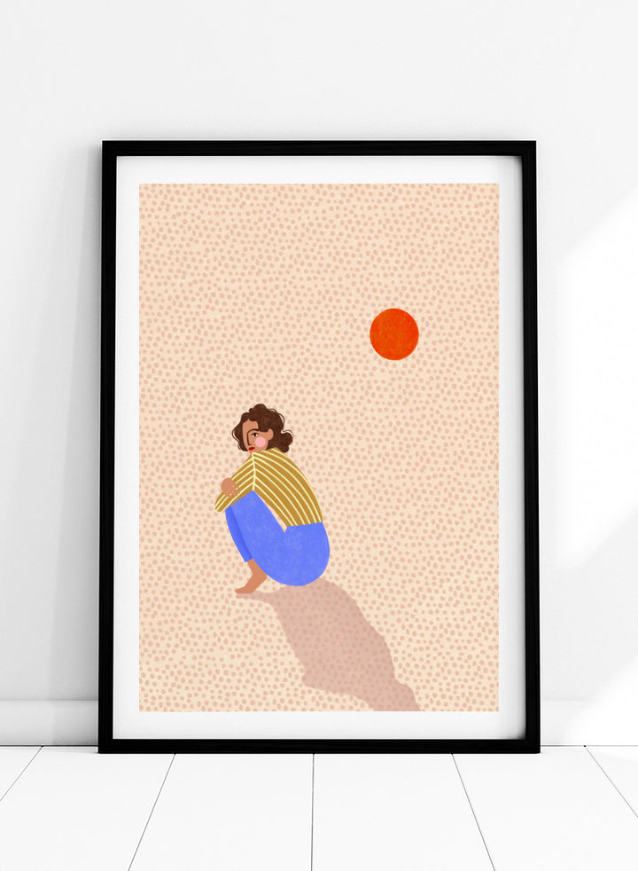 A minimalist art print featuring a stylized illustration of a person crouching in blue pants and a yellow striped top, looking up at a small orange sun against a light beige dotted background, framed with a white mat and black border. Pensive Woman Under Sun by Bea Müller art print featuring a seated woman beneath an orange sun in bold blue, mustard, and soft neutral tones.