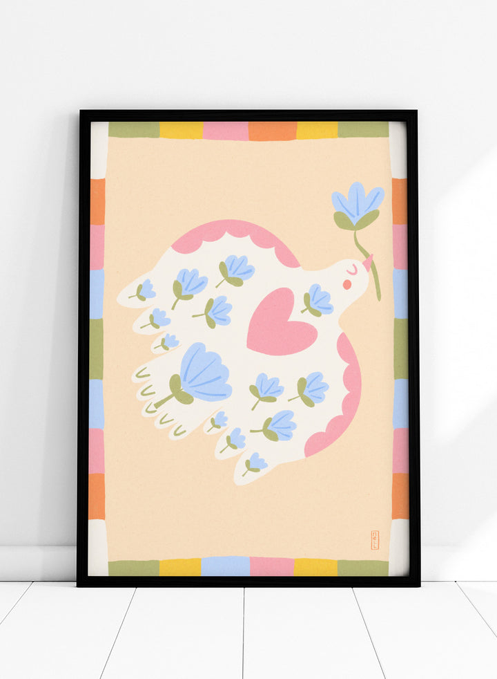 A framed art print featuring a whimsical illustration of a white dove with blue flowers and a pink heart, framed by a pastel multicolor border on a light peach background. Shop Flowering Peace Dove by Dirkie Nell, a colorful bird and floral art print featuring a white dove, blue flowers, pink wings, and a playful peace motif.