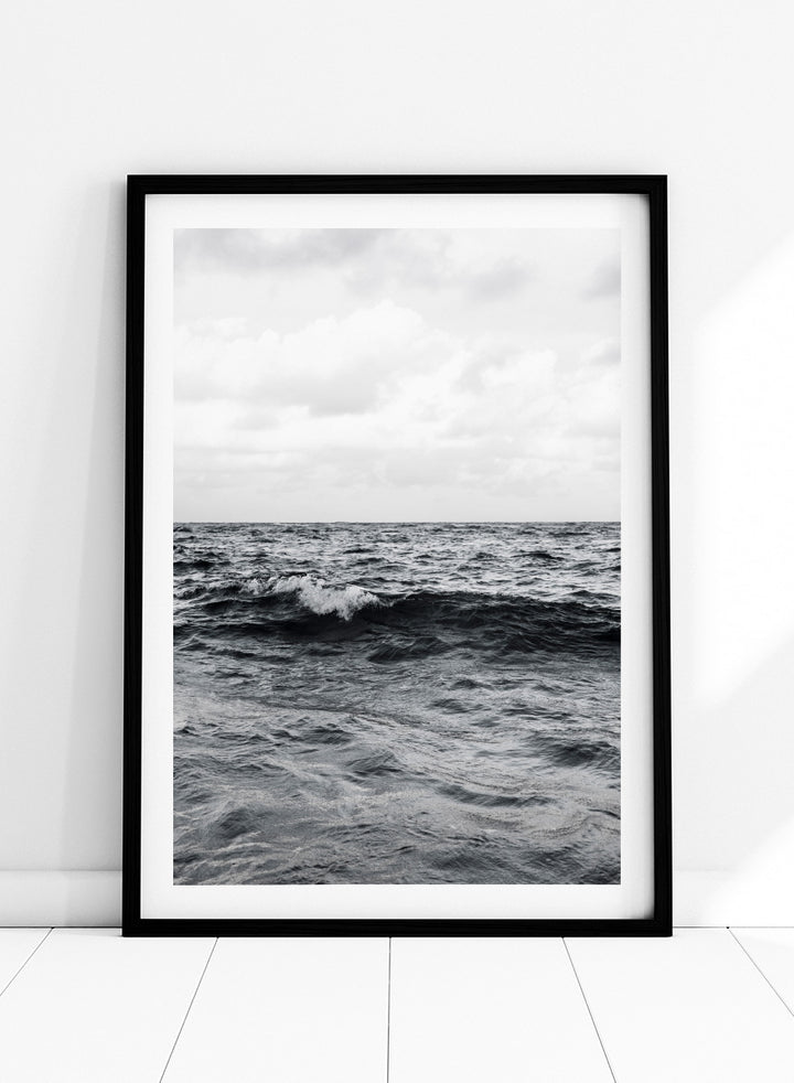 Black and white photographic art print of ocean waves under a cloudy sky. Endless Waves by Shot by Clint black-and-white ocean photography print featuring rolling water, textured surf, cloudy skies, and dramatic coastal movement.