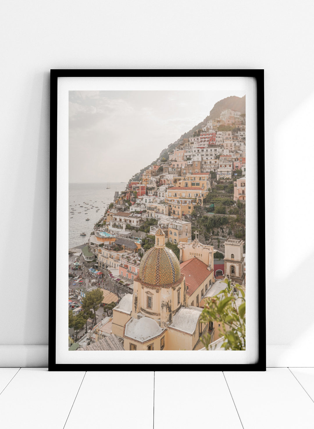 Hilly coastal town with buildings and a church dome. Positano Bliss by Henrike Schenk is a coastal photography print featuring the colorful hillside of Positano, Mediterranean architecture, and the beauty of the Amalfi Coast.