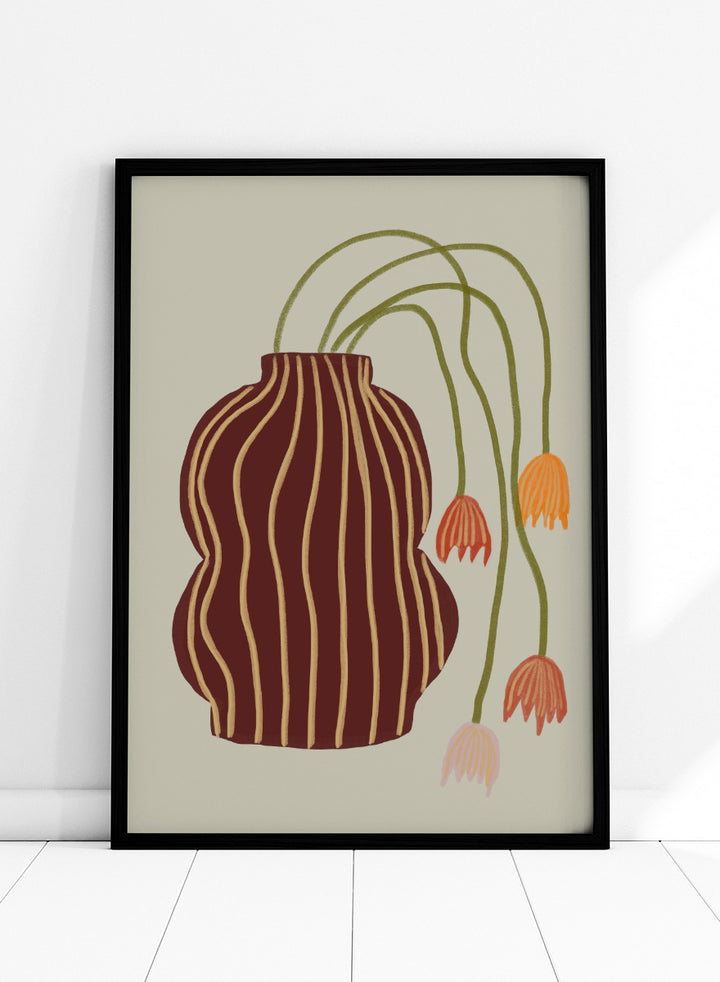 A stylized botanical art print featuring a dark brown vase with vertical gold stripes and several trailing flowers in orange, pink, and olive green on a warm beige background. Striped Vase Drooping Flowers by The Art Concept art print featuring a burgundy striped vase and soft drooping blooms in warm earthy tones.