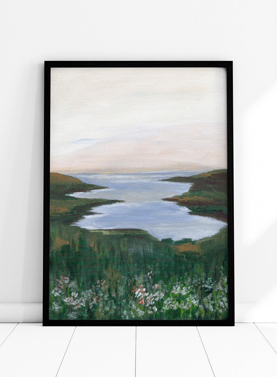 A landscape painting of a winding river or inlet between green hills, with a pale sky above and wildflowers in the foreground. Shop Wildflower Coast View by Nikita Jariwala, a coastal landscape wall art print poster featuring ocean views, green cliffs, wildflowers, and soft blue tones.