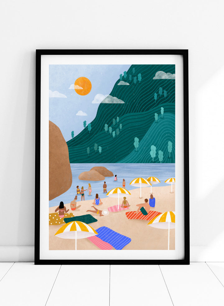 A framed art print featuring a stylized beach scene with a large teal-green mountain, blue water, a yellow sun, and beachgoers under striped umbrellas on a sandy shore. Relaxing Mountain Beach by Bea Müller coastal art print featuring swimmers, striped towels, yellow umbrellas, and a sweeping teal mountain.