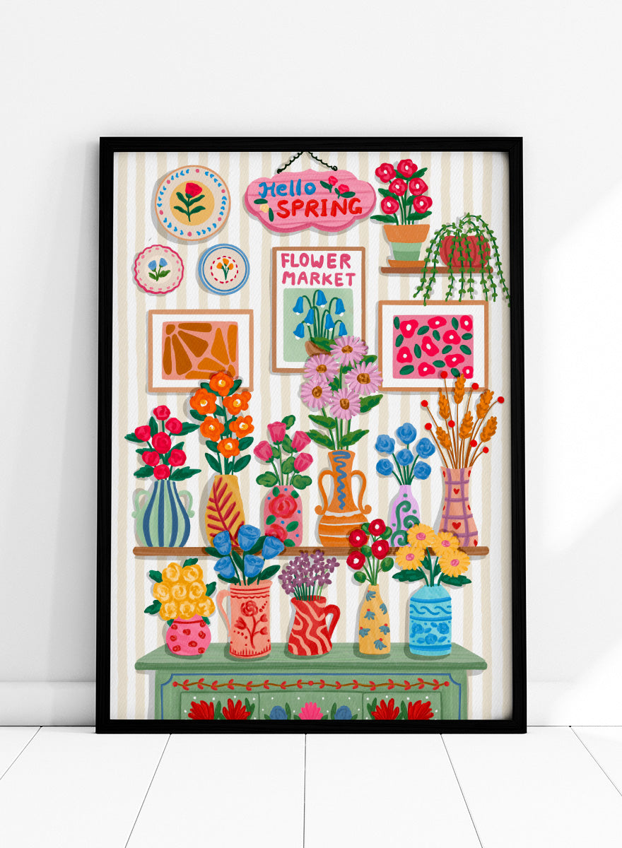 A colorful spring-themed floral wall display illustration featuring vases, framed art, hanging plants, and a sign reading 'Hello SPRING' and 'FLOWER MARKET' against a striped wall. Shop Hello Spring Flowers by Nidhi Kachhadiya, a colorful spring floral wall art print featuring bright flowers, decorative vases, and cheerful botanical details.