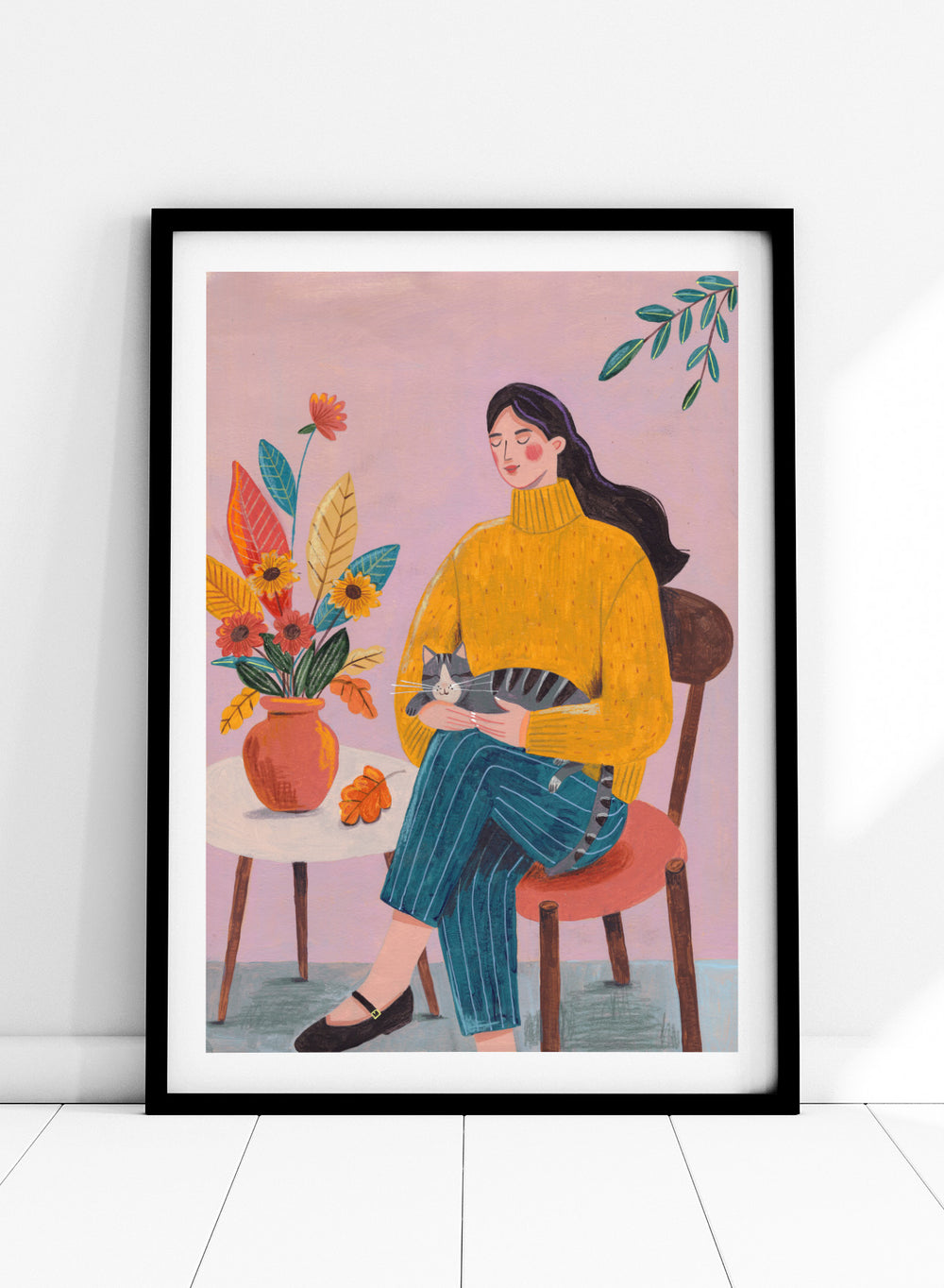 Illustration of a woman in a yellow sweater holding a cat, sitting by a table with flowers on a pink background. Peaceful Woman and Cat by Caroline Bonne Müller is a fine art print and wall poster featuring a woman holding a cat beside a floral arrangement.