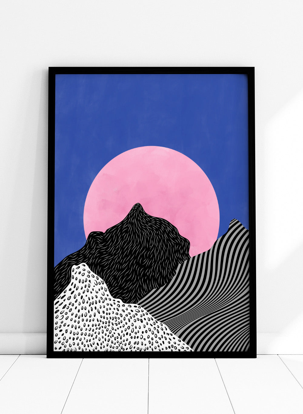 Artistic depiction of mountains with a pink moon in a blue sky. Surreal Peaks View by Elena Ristova is a minimalist abstract landscape print with bold mountains and a pink sun. Officially licensed wall poster with framing.