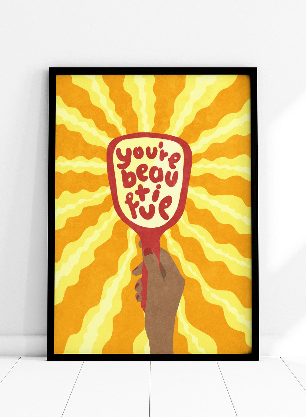 Hand holding a sign with 'You're beautiful' on an orange and yellow background. Beautiful by Raissa Oltmanns is a modern motivational art print featuring a hand mirror illustration, bold lettering, and bright statement wall poster style.