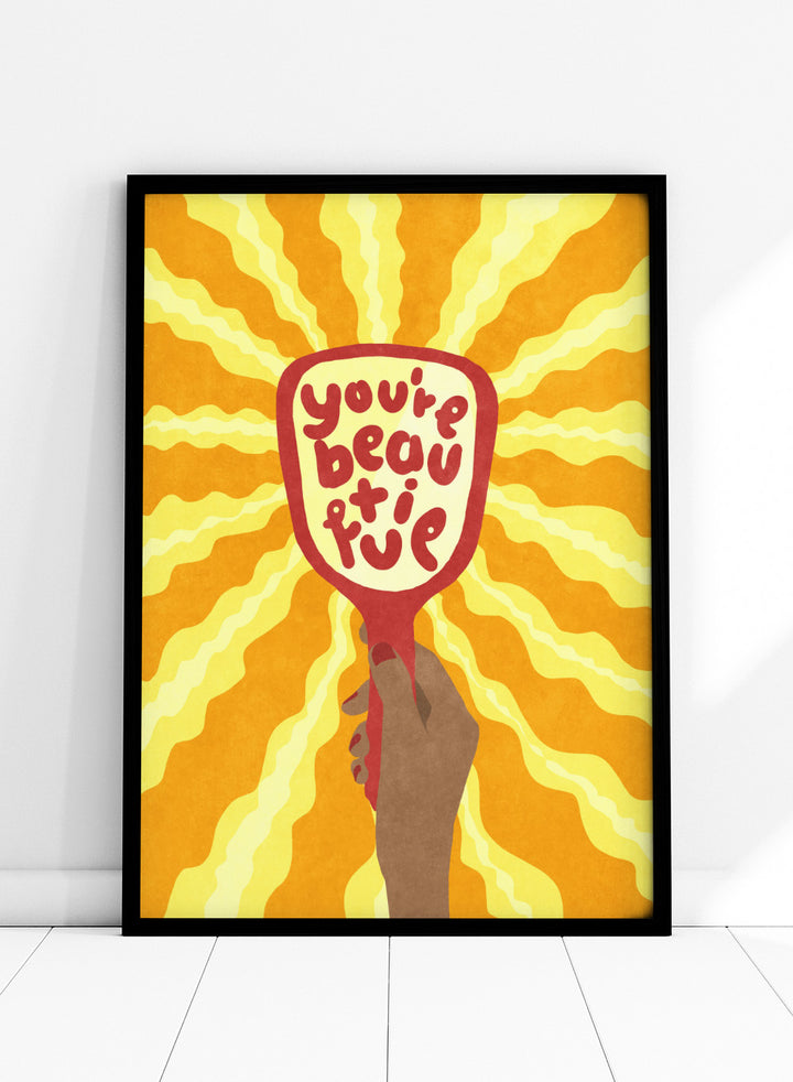 Hand holding a sign with 'You're beautiful' on an orange and yellow background. Beautiful by Raissa Oltmanns is a modern motivational art print featuring a hand mirror illustration, bold lettering, and bright statement wall poster style.