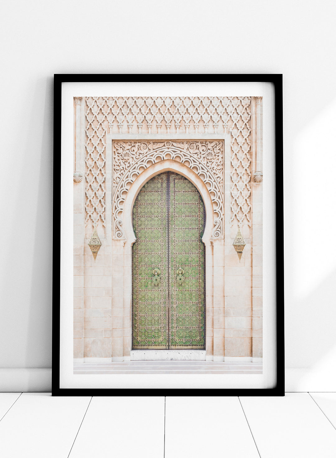 Decorative archway with ornate green door on a light stone wall. Ornate Moroccan Green Door by Henrike Schenk is a Moroccan architecture print featuring an ornate green door, Islamic patterns, and historic stone details.