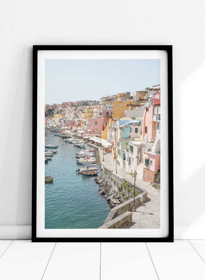 Colorful coastal town with boats docked along a waterfront. Colorful Italian Harbor by Henrike Schenk is a coastal photography print featuring pastel waterfront architecture, fishing boats, turquoise waters, and Mediterranean charm.