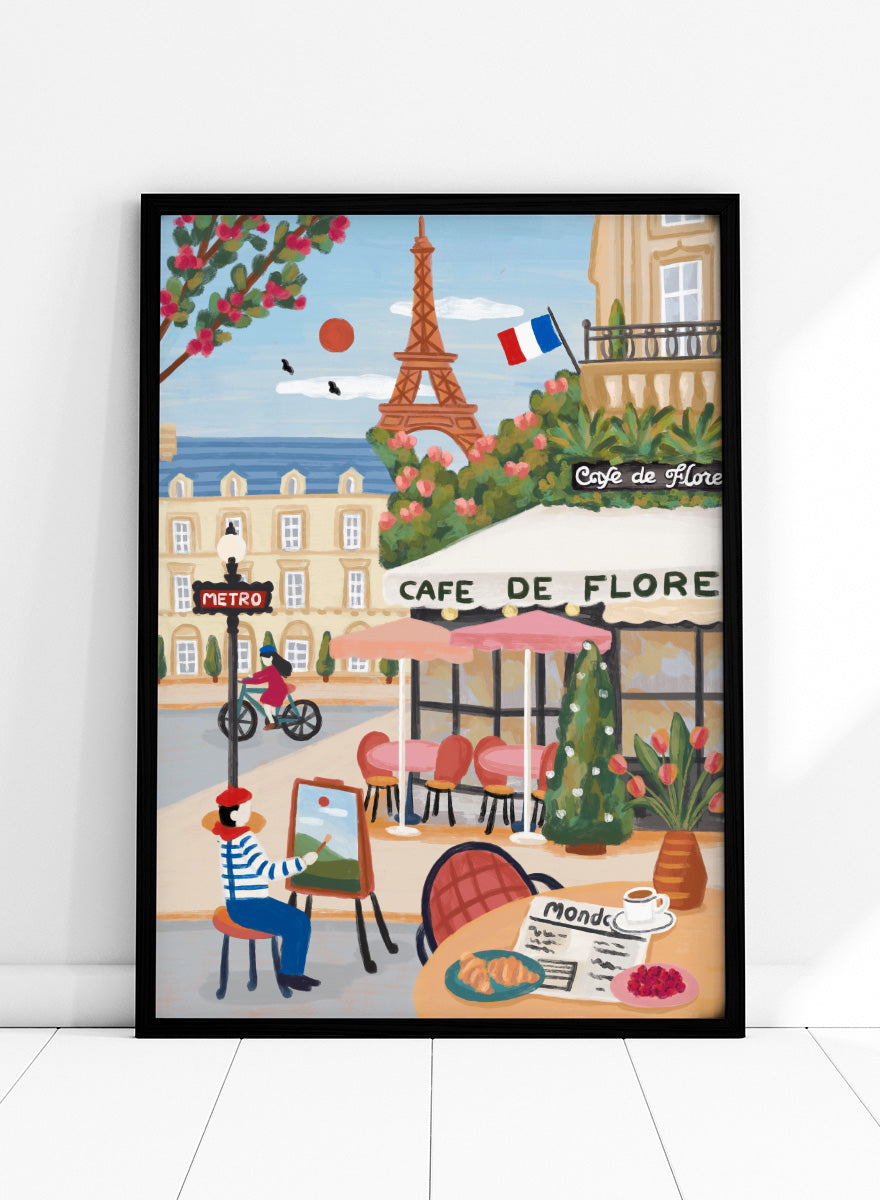 A colorful illustrated Paris street scene with the Eiffel Tower, a cafe exterior labeled Cafe de Flore, a cyclist, a seated painter, flowers, and a French flag. Shop Paris Cafe Life by Nidhi Kachhadiya, a colorful Paris wall art print inspired by French café culture, the Eiffel Tower, and charming European city life.