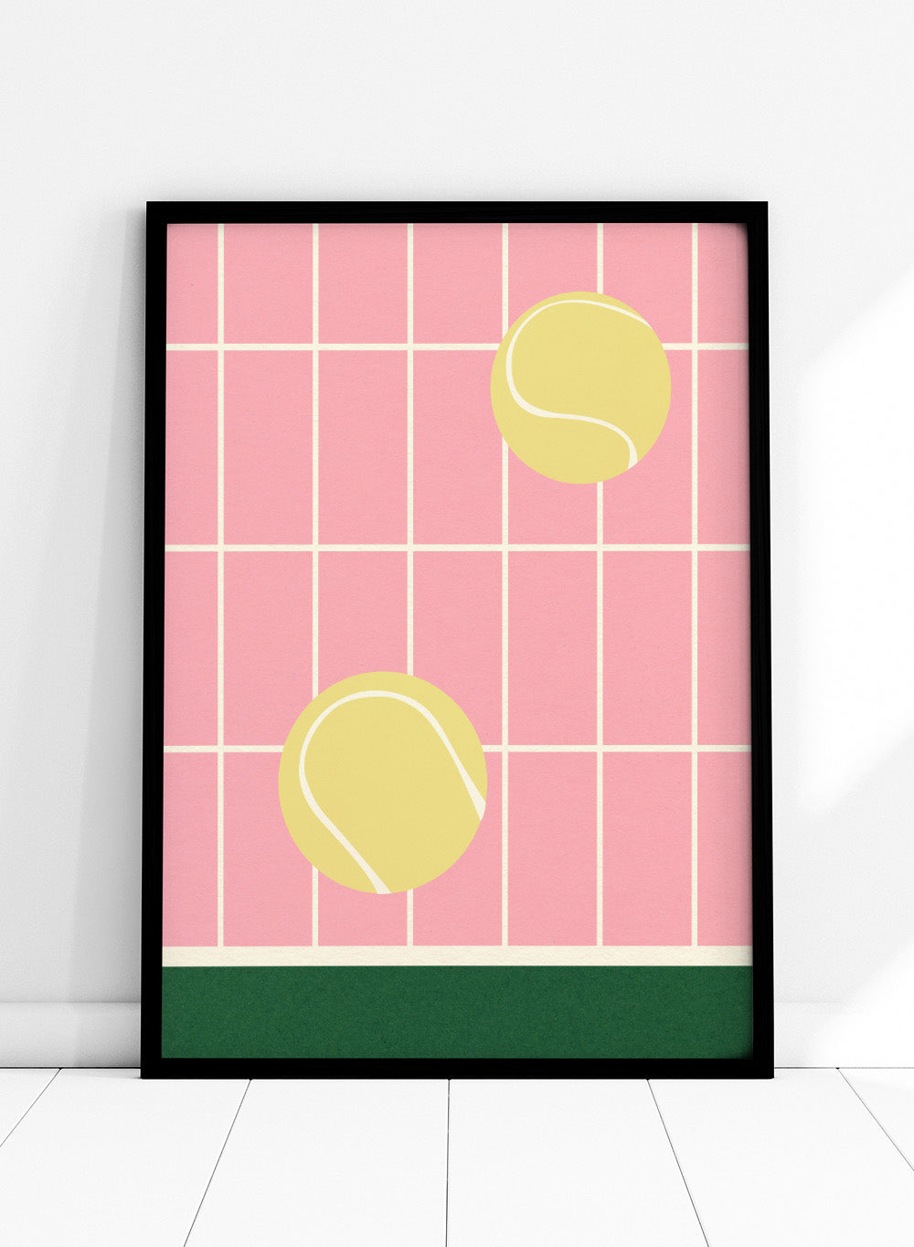 Two yellow tennis balls on a pink grid background with a green stripe at the bottom. Tennis Kitchen by Rosi Feist is a modern minimalist fine art print featuring oversized tennis balls on pink tile. Officially licensed wall poster with optional artisan framing.