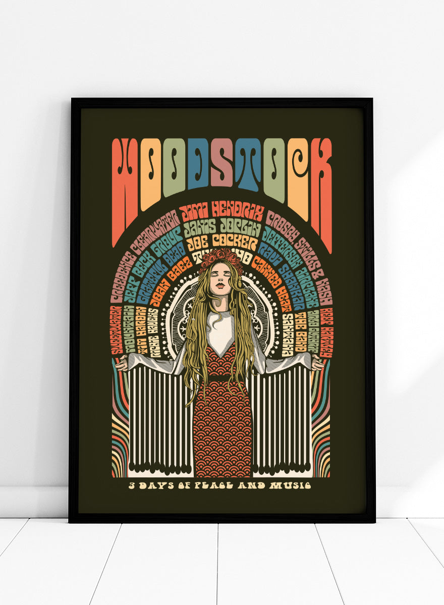 A framed psychedelic art poster featuring the word 'WOODSTOCK' in large multicolored letters at the top, an illustrated woman in a red patterned dress with long blonde hair in the center, and text reading '3 DAYS OF PEACE AND MUSIC' at the bottom, all on a dark olive background. Woodstock Peace Festival by Retrodrome retro music art print featuring 1969 festival typography, psychedelic color, and a bold peace-and-music theme.