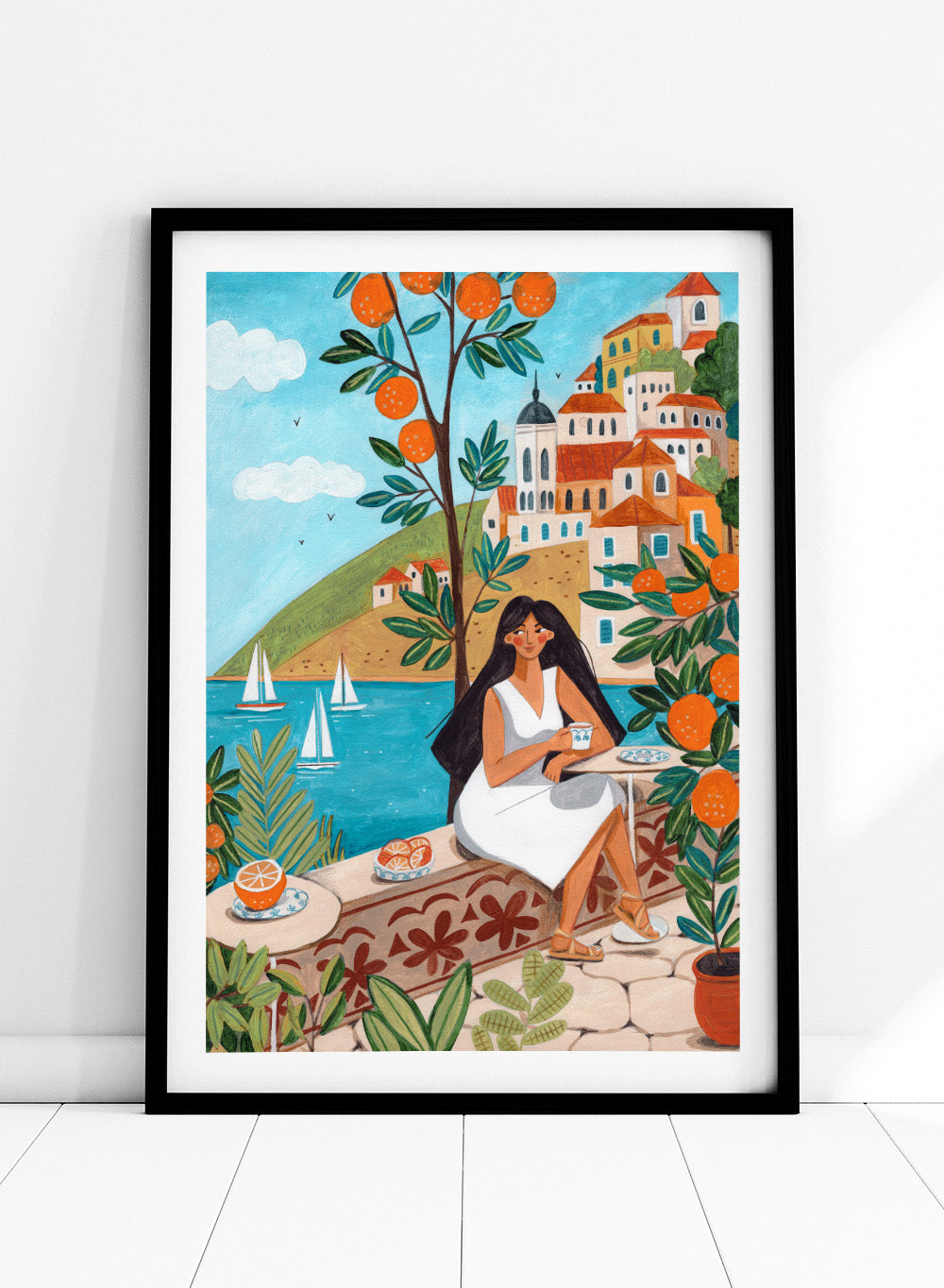 Woman in a white dress sitting under an orange tree with a scenic coastal town in the background. Mediterranean Orange Grove View by Caroline Bonne Müller fine art print, wall art poster with coastal scene, orange trees, modern aesthetic design