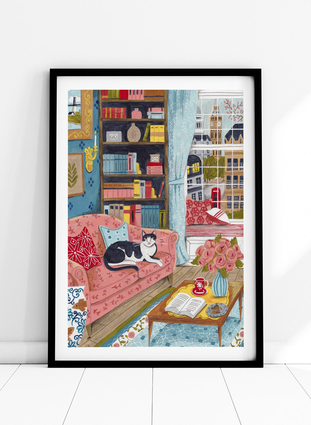 Illustration of a cozy living room with a cat on a pink sofa, bookshelf, and coffee table. Cozy London Cat by Caroline Bonne Müller is a fine art print and wall poster featuring a cat lounging in a colorful living room with a London city view.