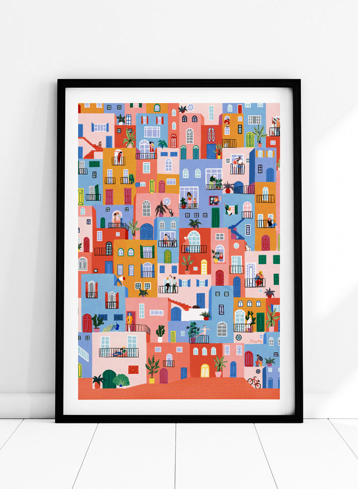 A framed art print featuring a colorful, whimsical illustration of Mediterranean-style buildings with people, animals, and plants. Colorful Town Life by Ceyda Alasar city art print featuring vibrant buildings, balconies, neighbors, plants, and lively urban details in bold color.