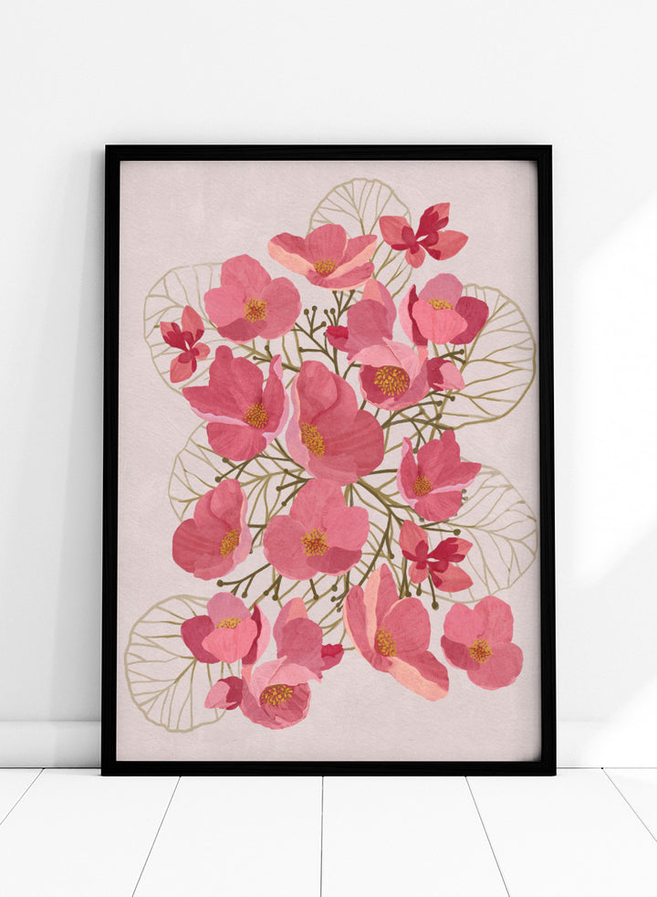 A framed botanical art print featuring pink flowers with yellow centers and delicate gold leaf outlines on a pale pink background. Shop Japanese Quince Floral Art Print by Katie O&