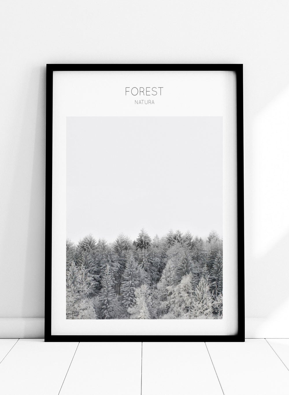 Black and white forest landscape with 'FOREST' and 'Natura' text at the top. Frosted Tranquility by The MIUUS Studio is a black and white forest photography art print and wall poster featuring snowy trees, minimalist composition, and modern neutral design.