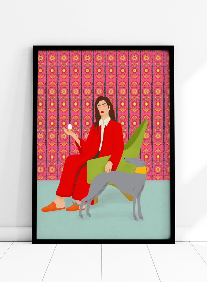 Woman in a red coat sitting on a green chair with a dog, against a pink patterned wall. Wonderful Egg by Jota de Jai is a whimsical modern art print of a woman in a red robe holding an egg with her greyhound, officially licensed wall poster with framing.