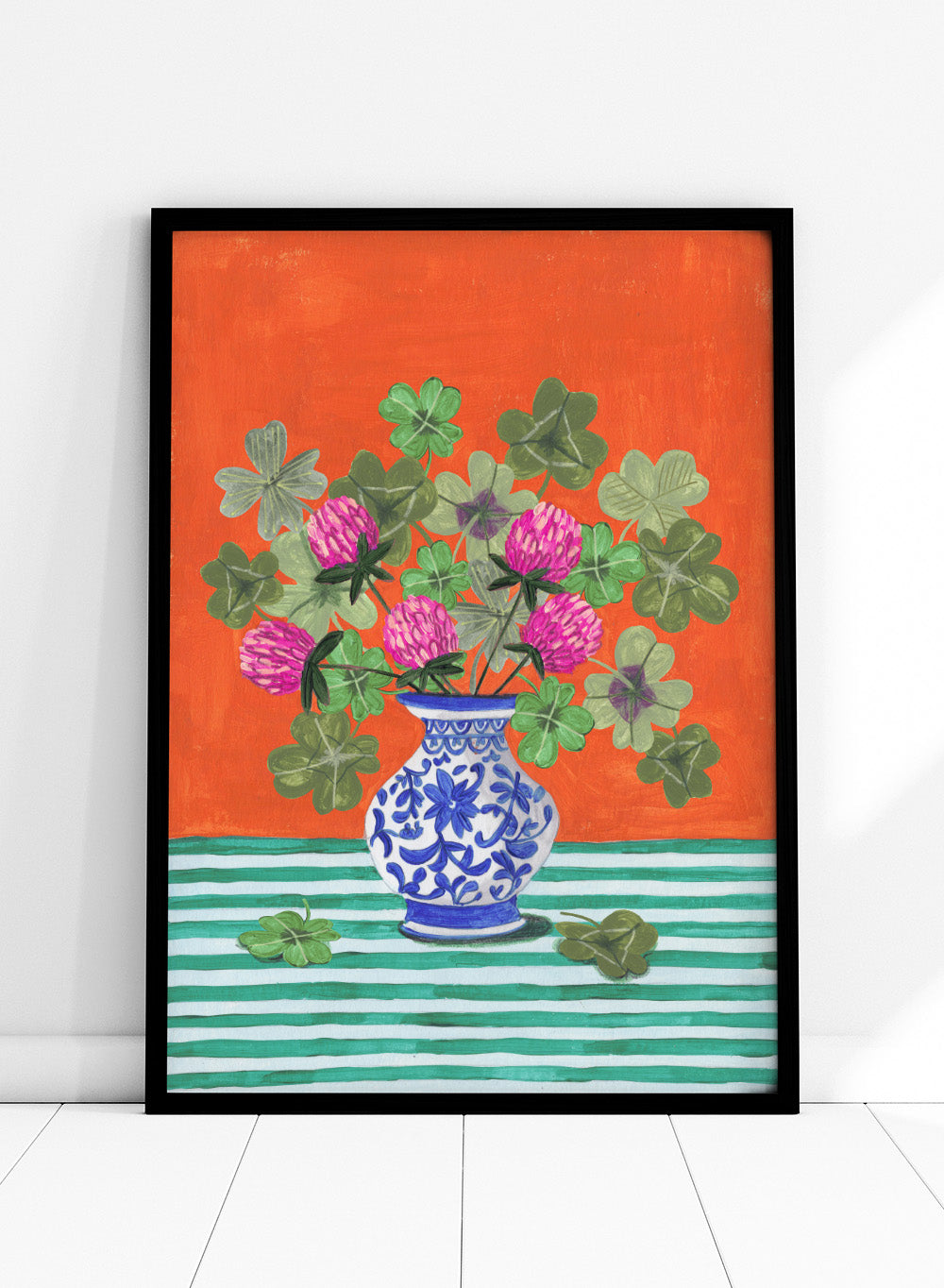Vase with pink flowers and green leaves on a red and green striped background. Vibrant Clover Still Life by Caroline Bonne Müller is a fine art print and wall poster featuring clover leaves, pink flowers, and a blue vase on a striped table.