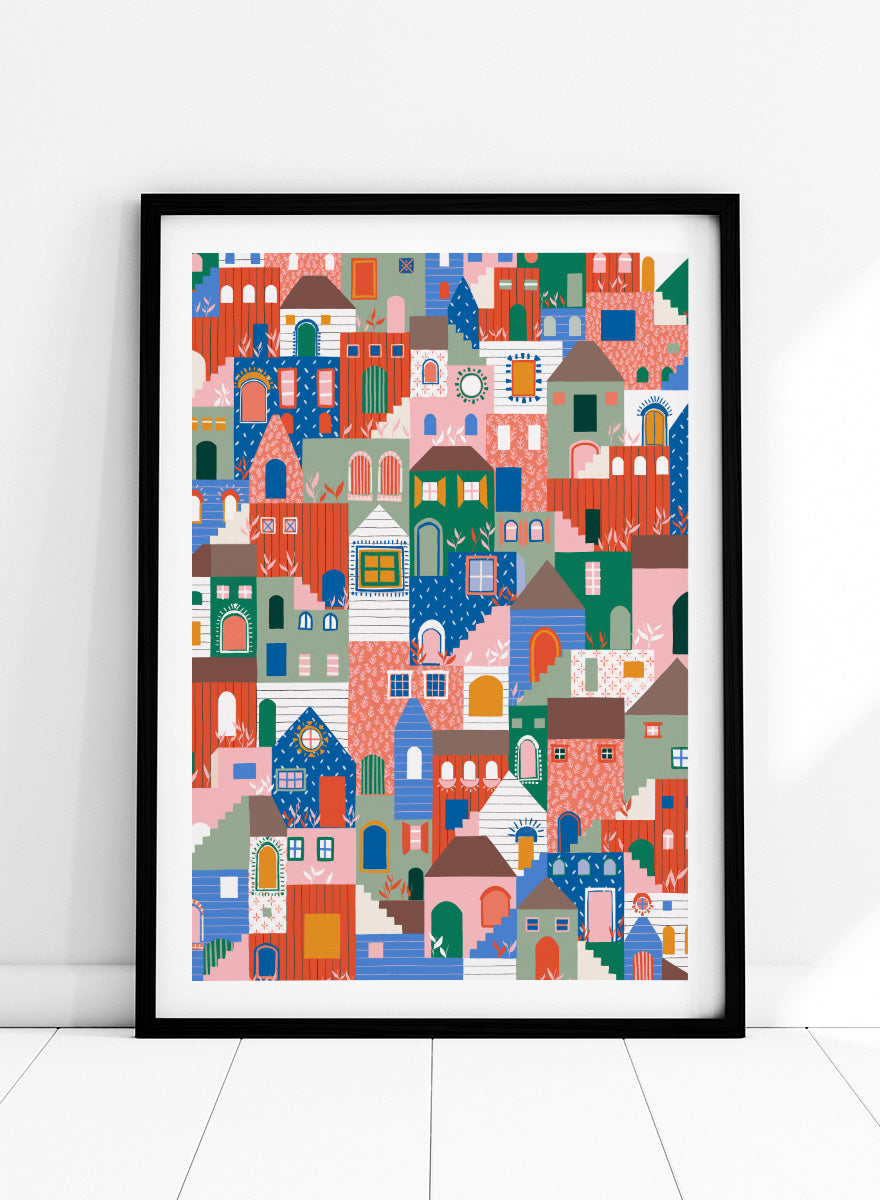A colorful art print featuring a dense, stylized illustration of houses and buildings in a playful, patterned village scene. Whimsical Cityscape Charm by Ceyda Alasar city art print featuring stacked colorful houses, patterned walls, winding stairs, and playful architectural details.