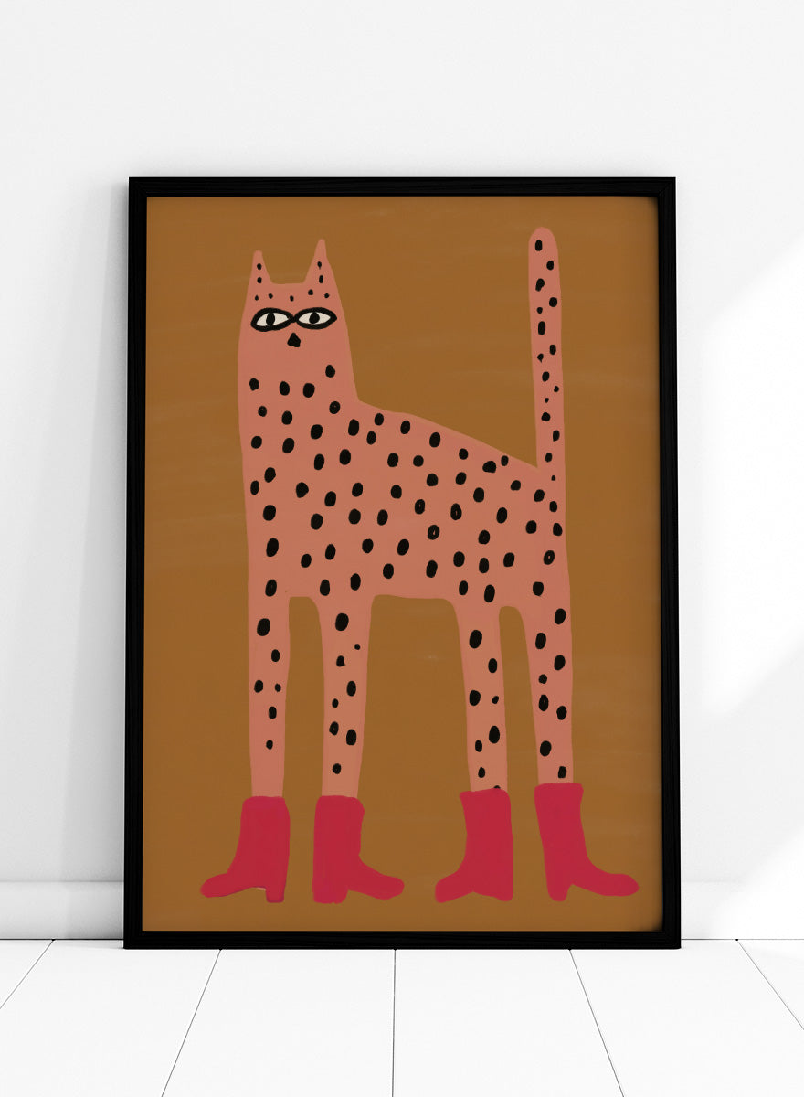 A stylized art print of a tall spotted cat in a pinkish-orange tone with black spots and bright pink boots, set against a warm brown background. Spotted Cat in Boots by The Art Concept playful cat art print featuring a pink spotted cat with long legs, red boots, and a warm ochre background.
