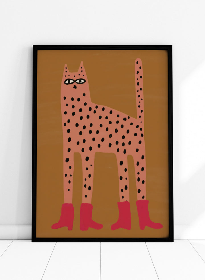A stylized art print of a tall spotted cat in a pinkish-orange tone with black spots and bright pink boots, set against a warm brown background. Spotted Cat in Boots by The Art Concept playful cat art print featuring a pink spotted cat with long legs, red boots, and a warm ochre background.