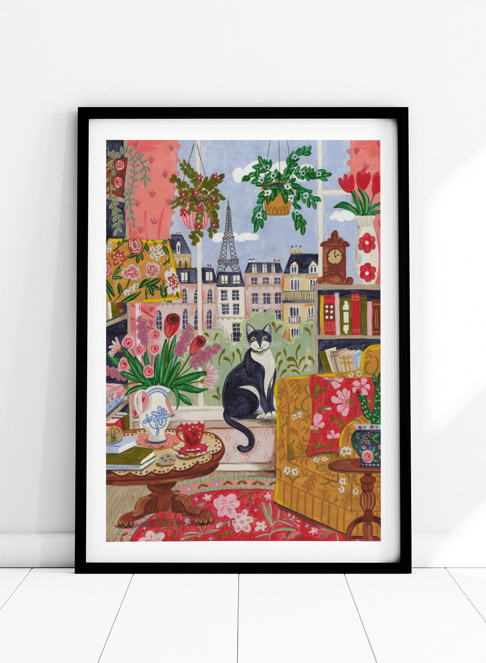 Colorful illustration of a living room with a cat, flowers, and a cityscape. Cozy Parisian Window Cat by Caroline Bonne Müller is a fine art print and wall poster of a cat by a window with Paris view and colorful interior.
