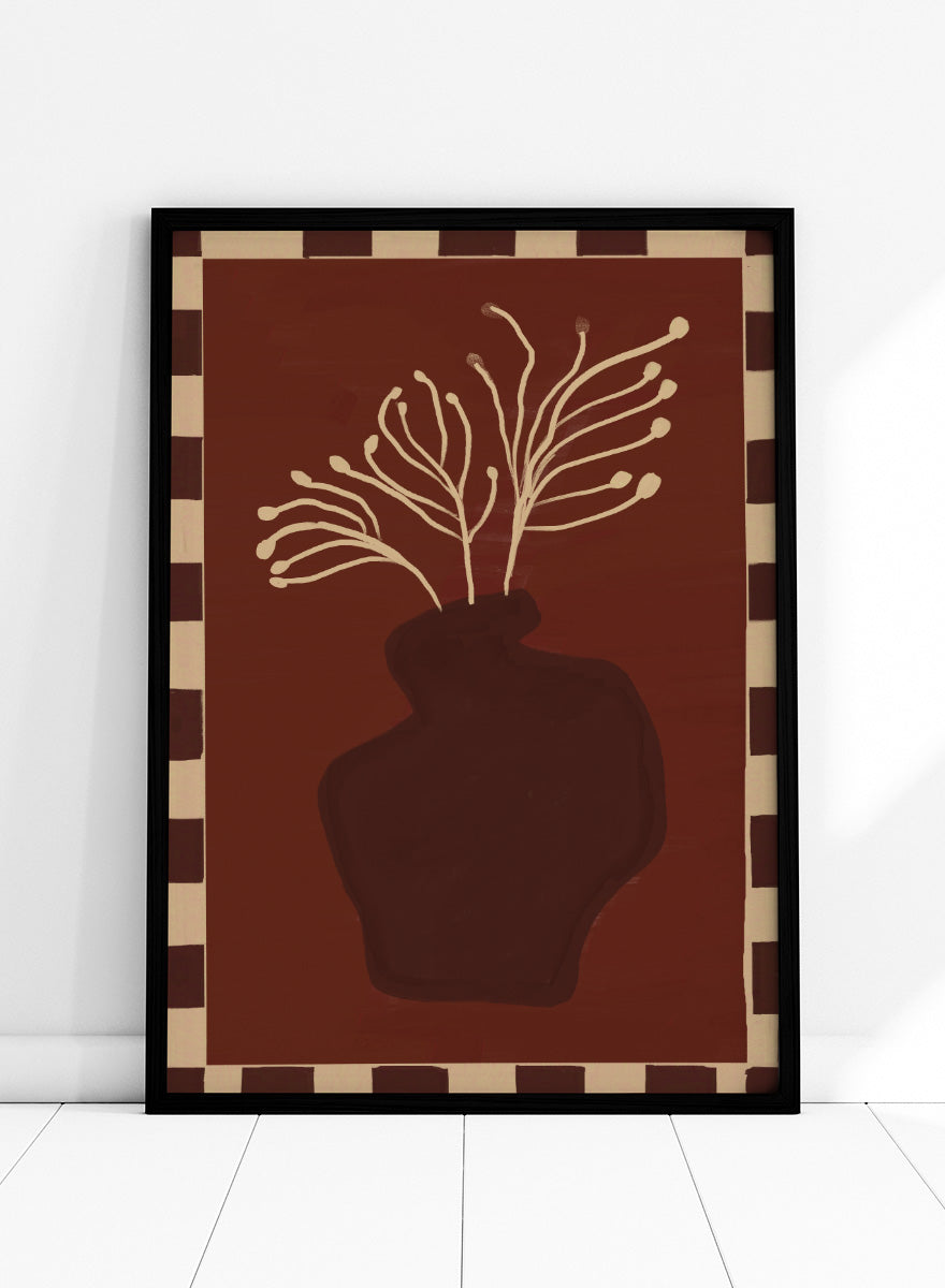An art print featuring a dark brown abstract vase with cream branching stems on a deep reddish-brown background, framed by a beige and dark brown checkered border. Minimalist Vase Plant by The Art Concept still life art print featuring a dark vase, cream stems, checkerboard border, and warm rust-brown tones.