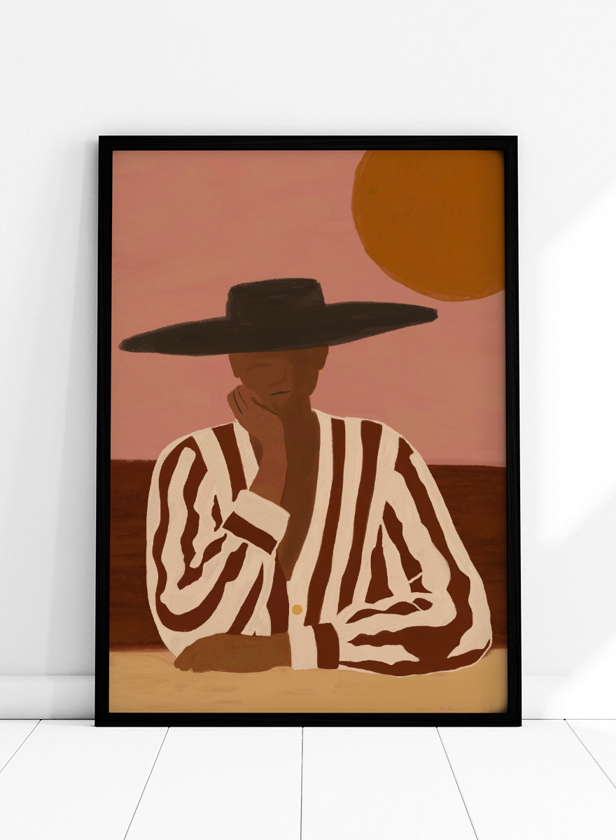 A stylized art print depicting a seated figure in a wide-brimmed black hat and a brown-and-white vertically striped shirt, set against a dusty pink sky with a large orange sun. Desert Dreamer by The Art Concept art print featuring a relaxed figure in a wide black hat, striped shirt, dusty pink sky, and warm desert-inspired tones.