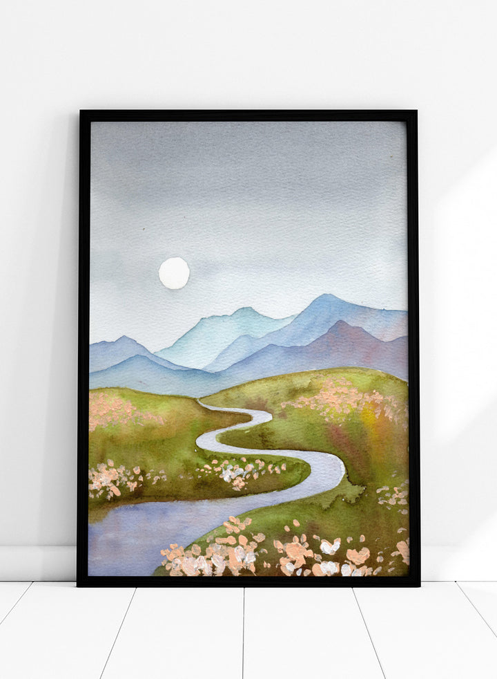 Watercolor landscape painting of a winding river flowing through green hills with pink flowers, blue mountains in the background, and a white sun in a gray sky. Shop Serene Mountain Path by Ekaterina Prisich, a landscape art print featuring a winding valley path, blue mountains, soft flowers, and a white moon.