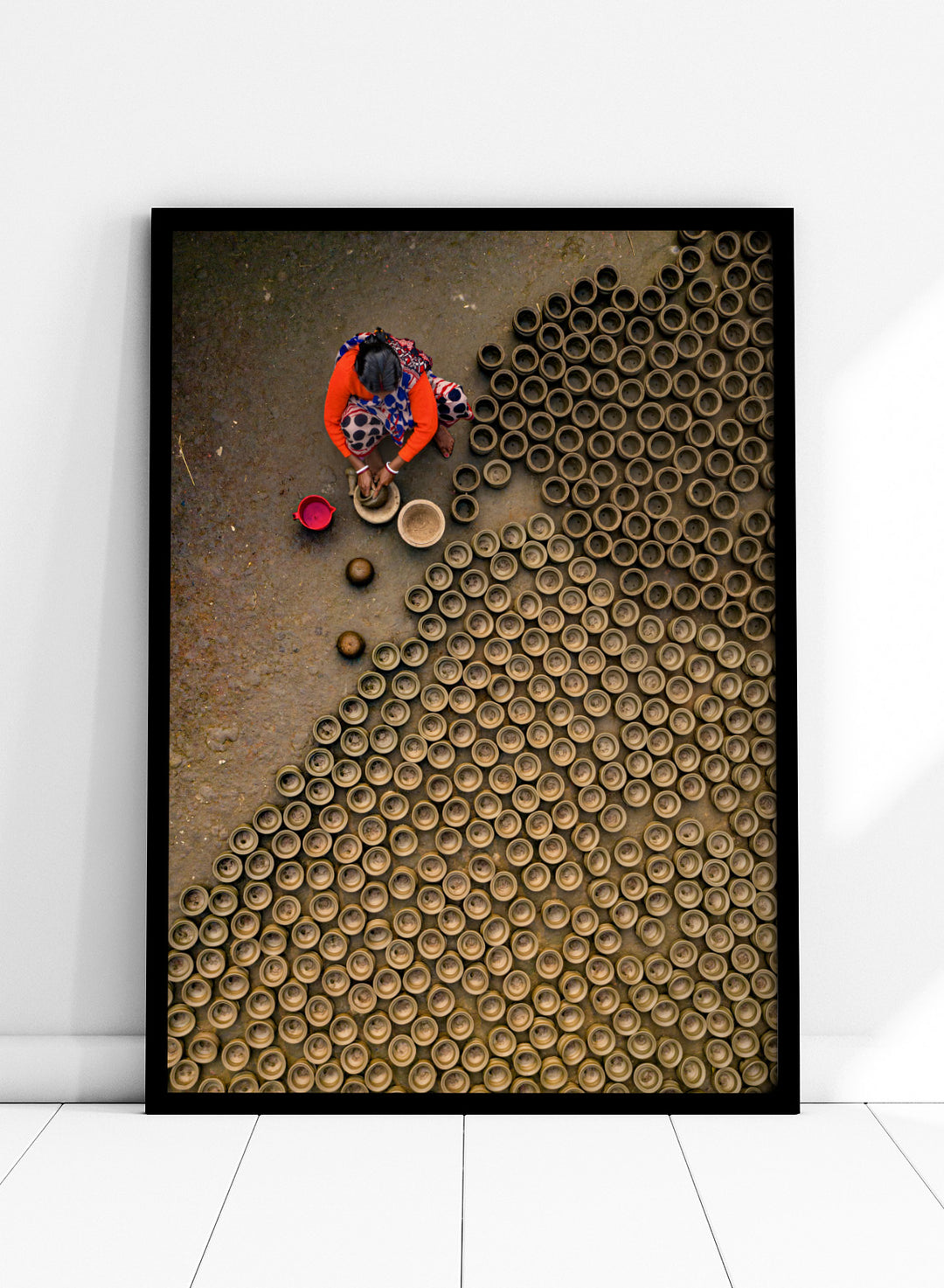 Person working with clay pots on a textured surface. Pot Making by Azim Khan Ronnie aerial photography print showing clay pots drying in Bangladesh village, traditional craft wall art poster