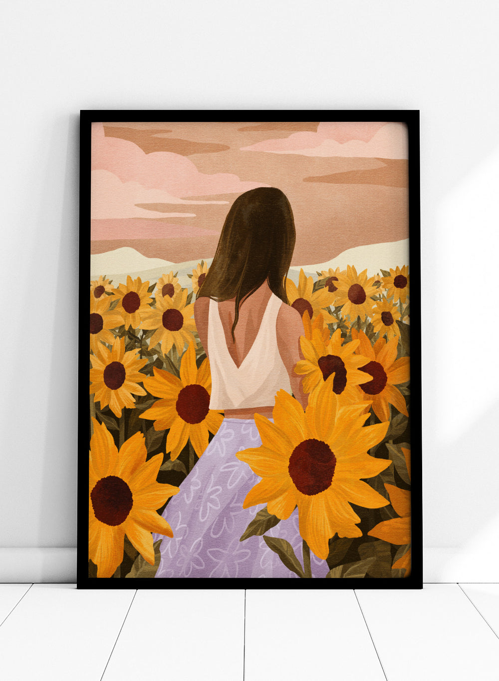 Woman in a white top and purple pants sitting among sunflowers with a scenic background. Sunflower Evenings by Goed Blauw is a fine art print and wall poster featuring a woman standing in a sunflower field with warm golden tones.