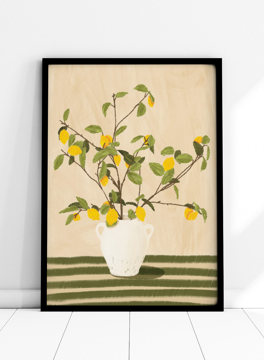 A framed still life artwork showing yellow lemons on leafy branches arranged in a white vase, set against a warm beige background with green horizontal stripes at the bottom. Lemon Tree Still Life by Lisa Solomoniuk premium framed fine art print featuring bright yellow lemons in a white vase on a striped green table.
